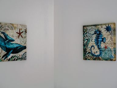 Two nautical-themed paintings on a white wall featuring a whale and a seahorse at Harbour Lights Port Isaac