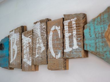 A close-up of wooden sign letters spelling beach on a white wall at Harbour Lights Port Isaac