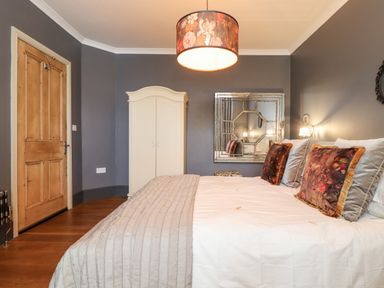 A bedroom with a wooden door white wardrobe large mirror and a bed with decorative pillows at Hillcroft in St Austell