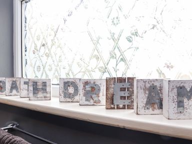 Decorative blocks spelling bath dream on a windowsill with frosted window glass in a bathroom at Hillcroft in St Austell
