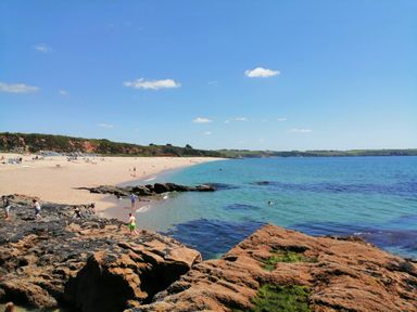A sandy beach with rocks and people near the water at Hillcroft in St Austell