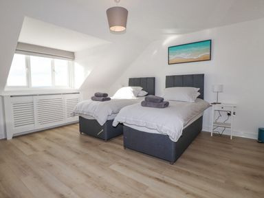 A bedroom with two single beds bedside table and a window at Tarth Y Mor in Criccieth