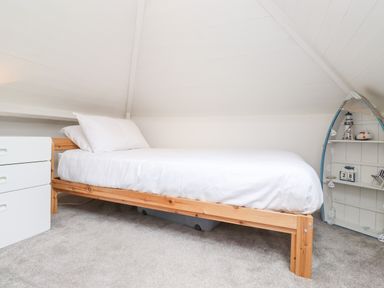 A bedroom with a single bed white bedding a white dresser and a small boat shaped shelf at Canny Cottage Low Hauxley Nr Amble