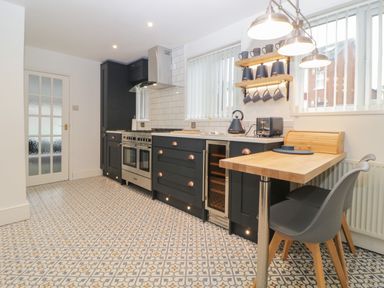 A kitchen with black cabinets a stainless steel oven wooden countertop and patterned floor tiles at Cornerside in Sidmouth