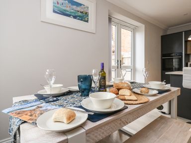 A dining table set with bowls plates bread and wine in a kitchen at 3 Compass Point in Weymouth