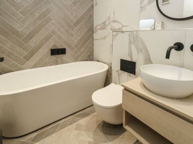 A bathroom with a bathtub toilet and a sink on a wooden vanity at 3 Compass Point in Weymouth