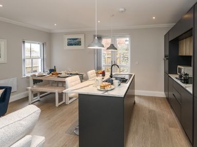 A kitchen and dining area with a central island and table set for dining at 3 Compass Point in Weymouth