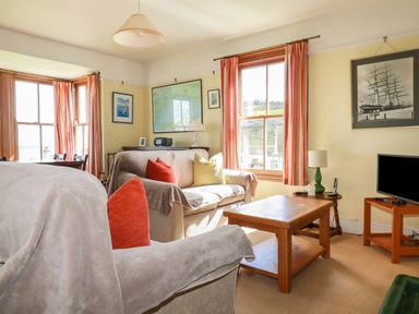 A living room with sofas cushions a wooden coffee table and framed pictures on the walls at Beachcliff in Gorran Haven