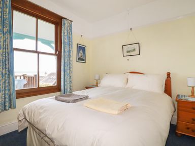 A bedroom with a double bed bedside tables lamps and framed pictures at Beachcliff in Gorran Haven