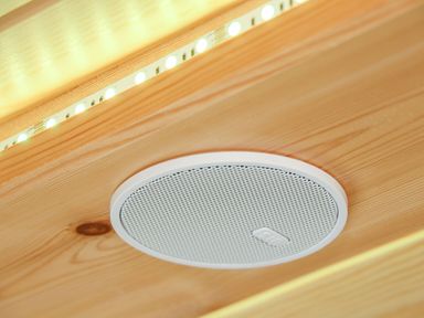 A wooden ceiling with a round white speaker and a strip of LED lights at Sun Rise in St Buryan