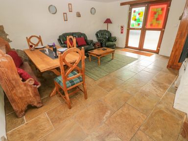 A living room with wooden dining table chairs green sofas coffee table and double doors with stained glass at Nook Bethesda near Narberth