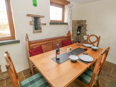 A dining room with a wooden table set with plates glasses and a wine bottle at Nook Bethesda near Narberth