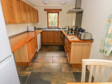 A U shaped kitchen with wooden cabinets a window above the sink and various appliances at Nook Bethesda near Narberth