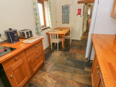 A kitchen with wooden countertops a toaster a bread jar a wooden table and two chairs at Nook Bethesda near Narberth