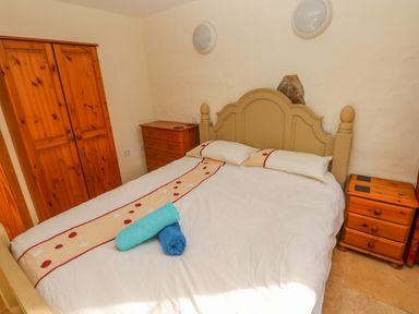 A bedroom with a double bed with pillows and towels two wooden nightstands and a wooden wardrobe at Nook Bethesda near Narberth