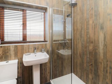 A bathroom with a toilet sink and glass shower enclosure at Causeway Cottage in Holy Island