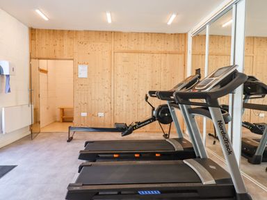 A fitness room with two treadmills and a rowing machine with wooden panel walls and mirrored sliding doors at Strawberry Bank - Kingfisher in Pyworthy near Bridgerule