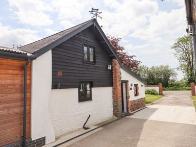 An exterior view of a house with black and white walls and a driveway at Strawberry Bank - Kingfisher in Pyworthy near Bridgerule