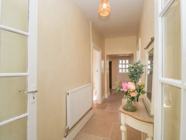 A hallway with a vase of flowers on a small table a radiator and a door at The Hame in Monmouth
