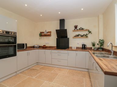 A kitchen with wooden countertops white cabinets a double oven microwave sink and plants at The Hame in Monmouth