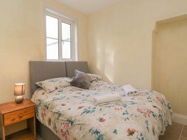 A bedroom with a double bed a bedside table with a lamp and a window at The Hame in Monmouth
