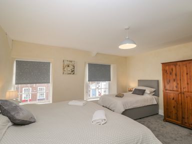 A bedroom with two beds a wooden wardrobe lamps and two windows with blinds at The Hame in Monmouth