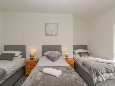 A bedroom with three single beds and two wooden nightstands with lamps at The Hame in Monmouth