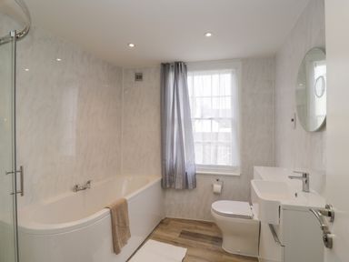 A bathroom with a bathtub shower toilet sink mirror and window with curtains at The Hame in Monmouth