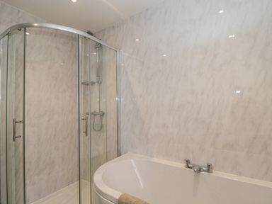 A bathroom with a glass shower enclosure and a white bathtub at The Hame in Monmouth
