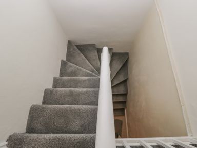 A staircase with grey carpet and a white railing at The Hame in Monmouth