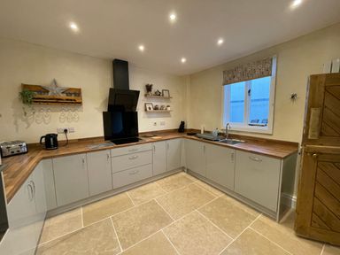 A kitchen with wooden countertops gray cabinets a window toaster kettle and sink at The Hame in Monmouth
