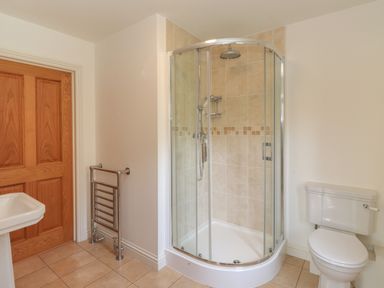 A bathroom with a corner shower enclosure toilet sink and towel rack at Whin Hill Cottage in Craster