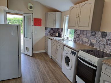 A kitchen with white cabinets appliances and patterned tile backsplash at Bogrie Cottage in Canonbie near Gretna Green