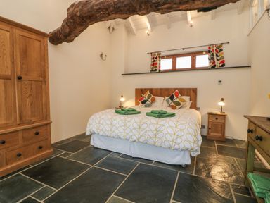 A bedroom with a double bed two bedside tables a wooden wardrobe and a wooden desk at The Threshing Barn in Highampton