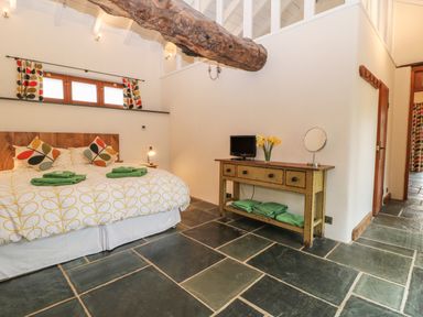 A bedroom with a double bed and green towels on a tiled floor at The Threshing Barn in Highampton