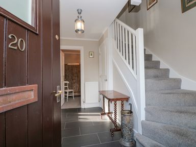 An open front door showing an entryway with a staircase a small table umbrella stand and a chair at Magnolia House in Dittisham