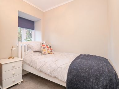 A bedroom with a single bed a bedside table with a lamp and a window with a blind at Magnolia House in Dittisham