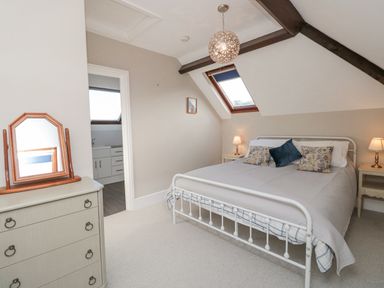 A bedroom with a double bed two bedside tables with lamps a chest of drawers with a mirror and a skylight window at Magnolia House in Dittisham