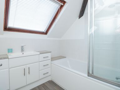 A bathroom with a bathtub a sink with cabinet and a skylight window at Magnolia House in Dittisham