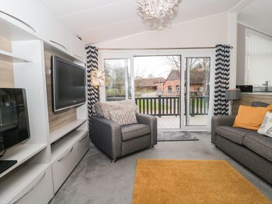A living room with two gray sofas a wall-mounted TV and sliding glass doors at Owls Nest in Furzehill