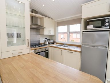 A kitchen with wooden countertops a gas stove an oven a kettle a toaster a window a microwave and a refrigerator at Lake View Lodge in Lakeside 3 White Cross Bay Windermere