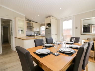 A dining table set with plates and glasses in a kitchen and dining area at Lake View Lodge in Lakeside 3 White Cross Bay Windermere