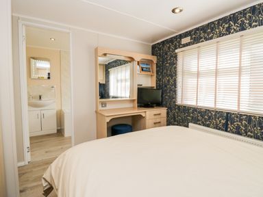 A bedroom with a bed desk with mirror and TV and an open door to a bathroom at Lake View Lodge in Lakeside 3 White Cross Bay Windermere