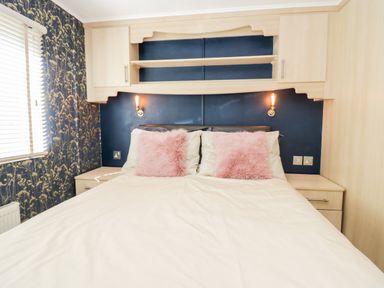 A bedroom with a bed white bedding pink pillows bedside tables and lamps at Lake View Lodge in Lakeside 3 White Cross Bay Windermere