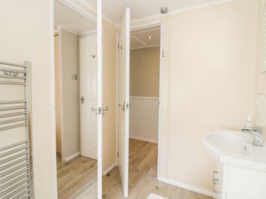 A bathroom with two white doors one with a mirror a stainless steel towel rack and a white sink at Lake View Lodge Lakeside 3 White Cross Bay Windermere