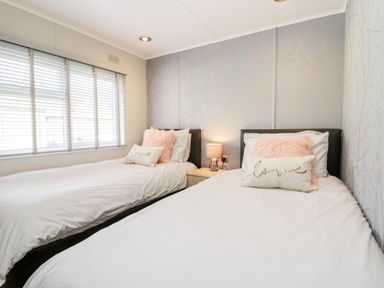 A bedroom with two single beds side by side white bedding and pillows with love text and a nightstand with a lamp between beds at Lake View Lodge in Lakeside 3 White Cross Bay Windermere