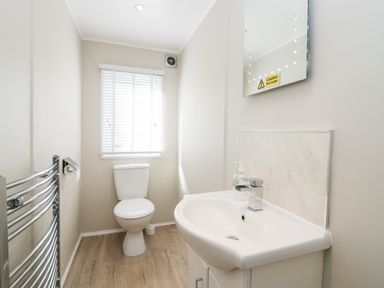 A bathroom with a toilet a sink a mirror and a towel radiator at Lake View Lodge in Lakeside 3 White Cross Bay Windermere