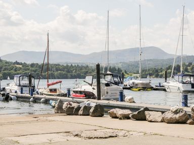 A boat dock with multiple boats moored and hills in the background at Lake View Lodge in Lakeside 3 White Cross Bay Windermere