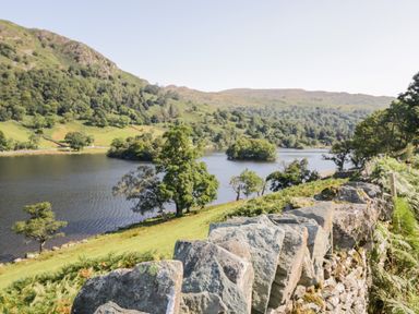 A lake with trees and hills in the background and a stone wall in the foreground at Lake View Lodge in Lakeside 3 White Cross Bay Windermere