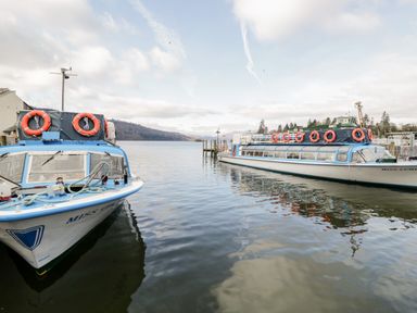 Two boats docked on a lake with hills and trees in the background at Lake View Lodge in Lakeside 3 White Cross Bay Windermere